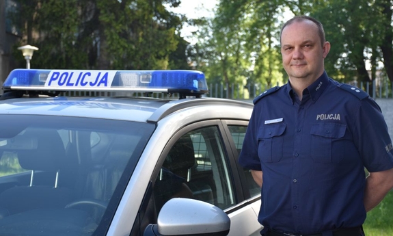 policjant stoi przy radiowozie