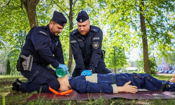 dwaj policjanci w trakcie zawodów - pokazuja udzielanie pierwszej pomocy na fantomie