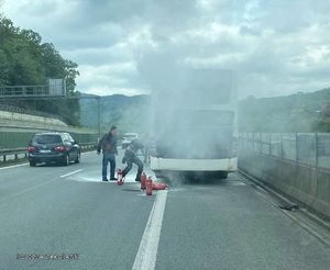 dwaj mężczyźni przy palącym się autobusie, obok stoją gaśnice