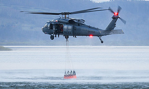 Policyjny śmigłowiec nabiera wody do zbiornika Bambi Bucket.