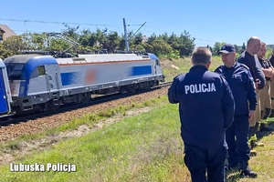 policjanci i strażacy stoją na górce przy torach