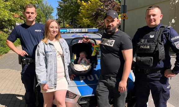policjanci wspólnie z rodzicami oraz dzieckiem w nosidełku