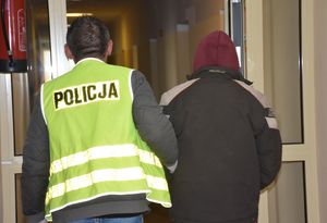 policjant prowadzi zatrzymanego