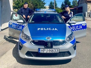 policjant i policjantka przy radiowozie