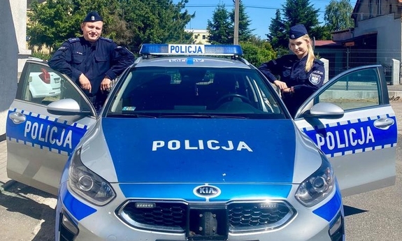 policjant i policjantka przy radiowozie