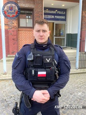 policjant stoi przed budynkiem policji