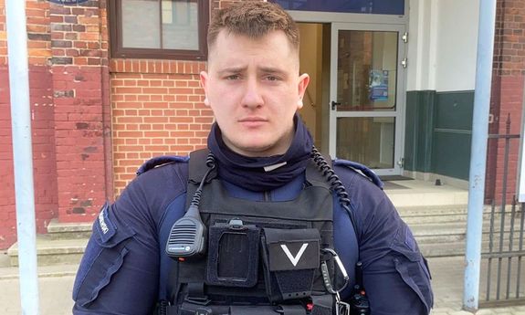 policjant stoi przed budynkiem policji