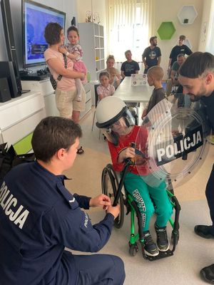 dziecko na wózku, obok niego dwaj policjanci