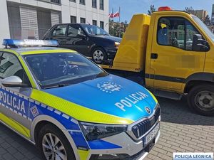 na zdjęciu radiowóz, w tle laweta holująca pojazd
