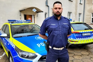policjant stoi przy radiowozie