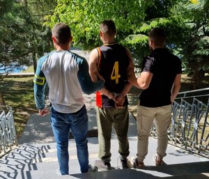 dwaj policjanci prowadzą zatrzymanego mężczyznę
