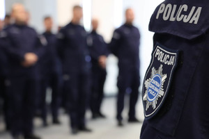 zbliżenie na rękaw policjanta z naszywką Centrum Szkolenia Policji, z tyłu widoczni policjanci