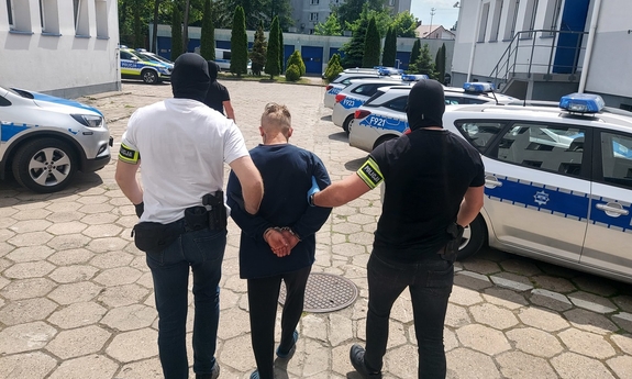 na zdjęciu dwóch policjantów prowadzi zatrzymanego mężczyznę