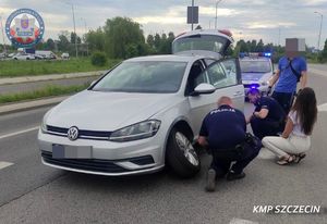 policjanci pomagają kobiecie wymienić koło