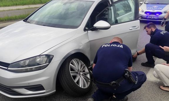 policjanci pomagają kobiecie wymienić koło
