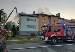 wóz strażacki, w tle dymiący się budynek