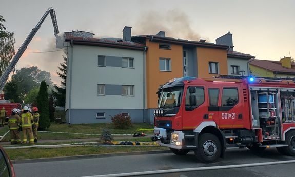 wóz strażacki, w tle dymiący się budynek