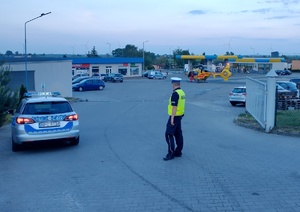 radiowóz i policjant. w tle śmigłowiec ratownictwa medycznego