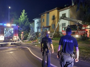 noc. policjanci i strażacy stoją przy budynku