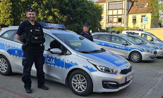 policjantka i policjant stoją przy radiowozie