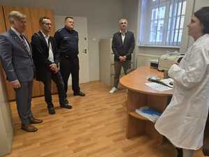kobieta w białym fartuchu, na przeciwko stoją goście