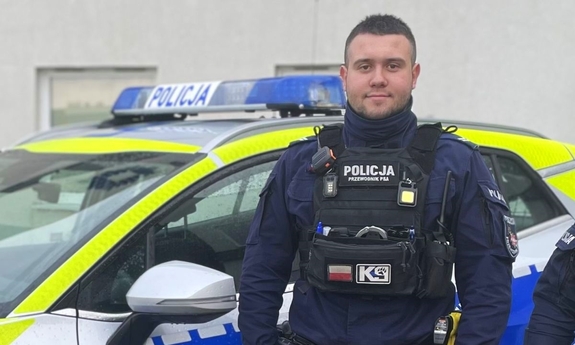 na zdjęciu umundurowany policjant, w tle radiowóz