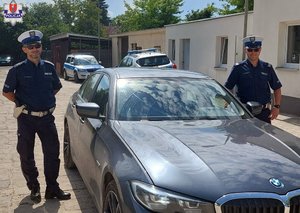dwaj policjanci ruchu drogowego stoją obok nieoznakowanego radiowozu