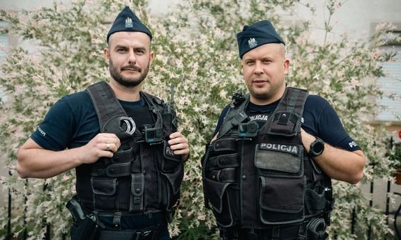 policjanci stoją na tle krzaków