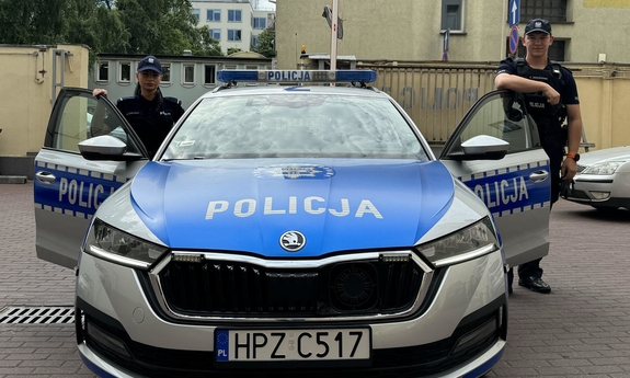 umundurowana policjantka i policjant stoją przy radiowozie