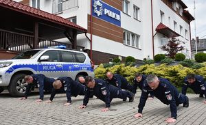 umundurowani policjanci przed budynkiem Komisariatu Policji w Pruchniku wykonują pompki