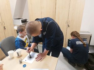 mężczyzna maluje pędzelkiem po kartce zbierając odciski