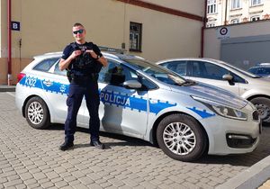 w mundurze, na tle policyjnego radiowozu stoi st. post. Tomasz Pipała