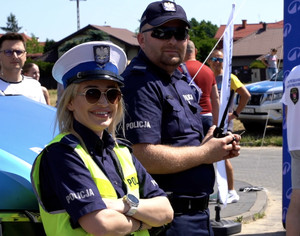 dwoje umundurowanych policjantów, za nimi widać kilka osób biorących udział w pikniku