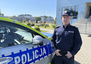 policjant stoi przy radiowozie policyjnym