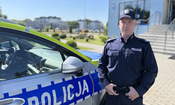 policjant stoi przy radiowozie policyjnym