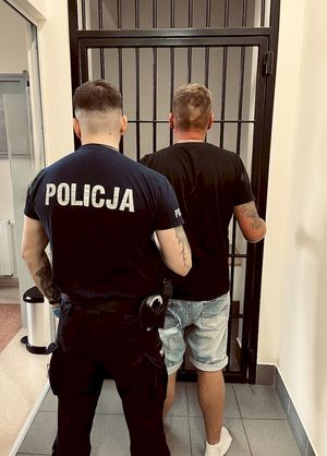 policjant stoi przed celą z zatrzymanym