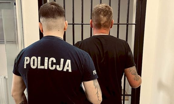 policjant stoi przed celą z zatrzymanym