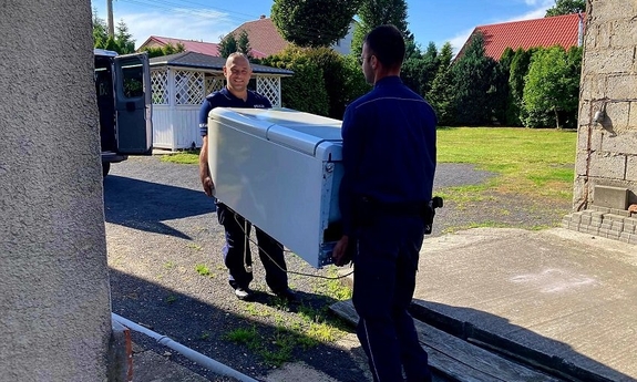 Dwóch policjantów niesie lodówkę