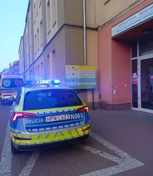 radiowóz zaparkowany przed wejściem do szpitala, w tle stoi karetka