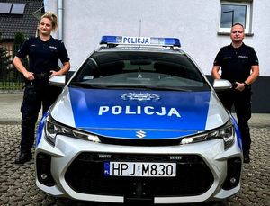 policjanci stoją obok radiowozu