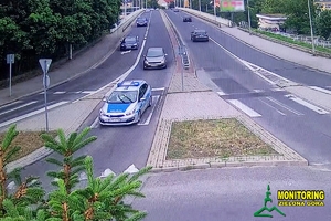 zdjęcie z monitoringu z widocznym na ulicy radiowozem policji na sygnale oraz jadącym za nim samochodem osobowym