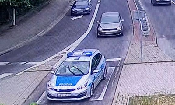 zdjęcie z monitoringu z widocznym na ulicy radiowozem policji na sygnale oraz jadącym za nim samochodem osobowym