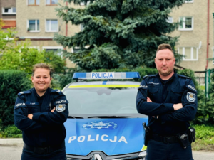 na zdjęciu umundurowani policjanci stoją przy radiowozie