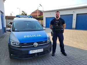 policjant stoi przy radiowozie