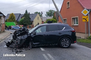 na zdjęciu rozbity samochód osobowy stoi na ulicy, w tle stoją funkcjonariusze i świadkowe wypadku