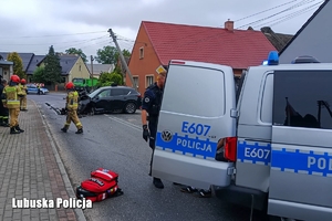 na zdjęciu radiowóz policyjny, w tle rozbity samochód, strażacy i świadkowie zdarzenia