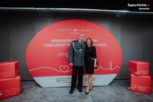 policjant pozuje z kobietą na dużej planszy z napisami Twoja krew moje życie