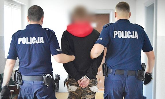 policjanci prowadzą zatrzymanego poszukiwanego