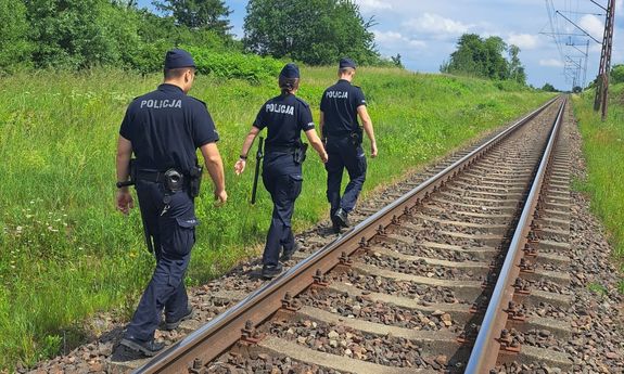 troje policjantów idących wzdłuż torów