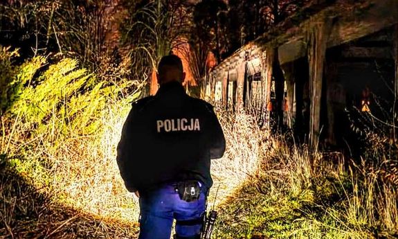 noc. policjant świeci latarką w las